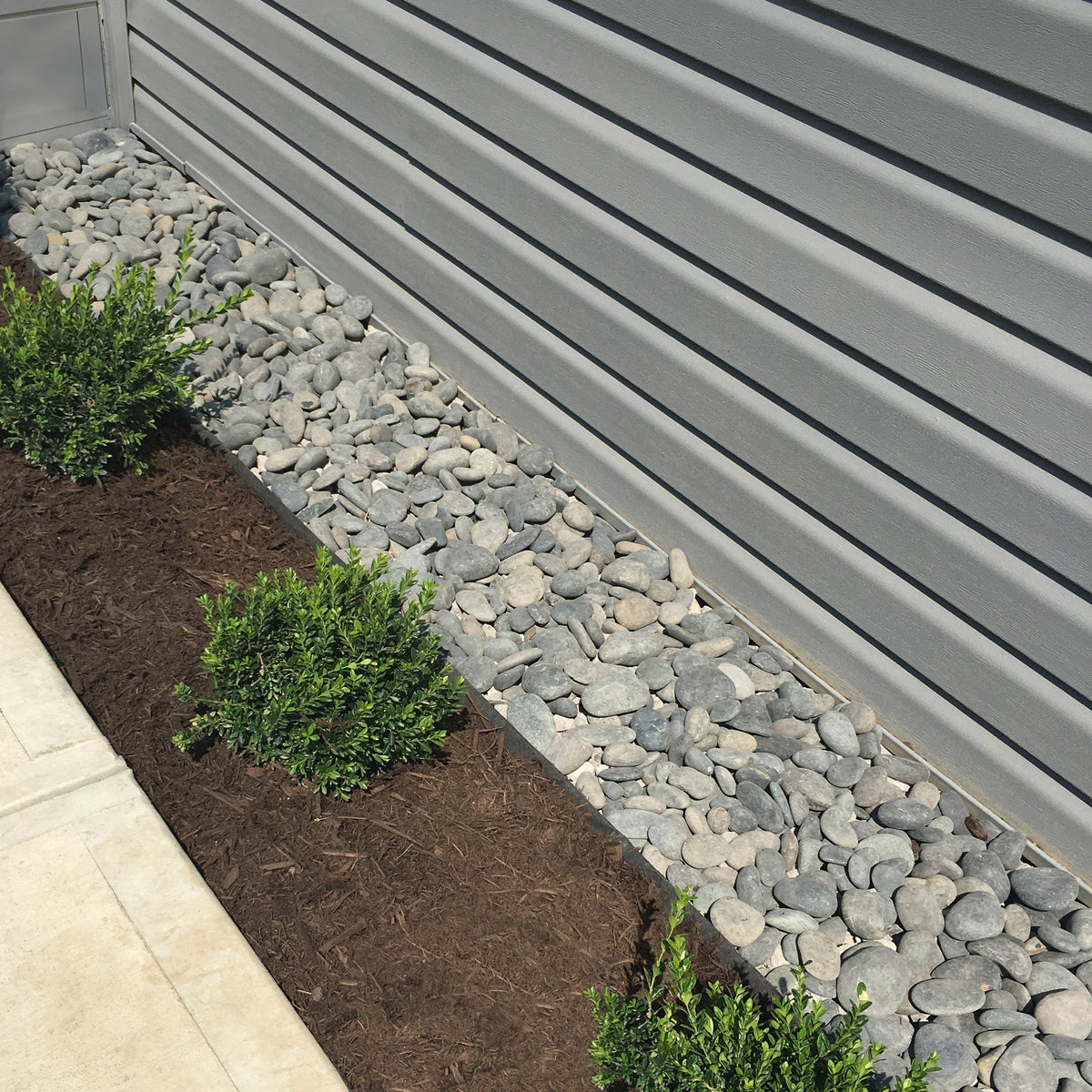 Grass Barrier between a gravel strip and a planting bed beside a house