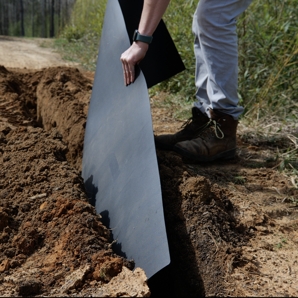 Installer setting a length of Bamboo Shield upright in a trench