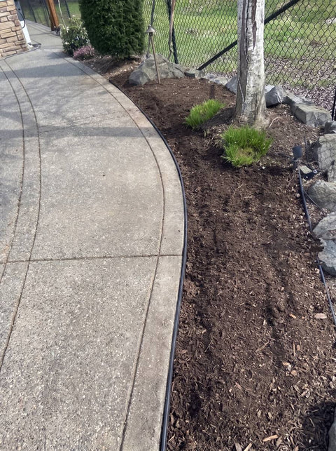 Sidewalk Shield installed along a paving edge — finished grade with only the barrier lip showing (Aaron Zappe)